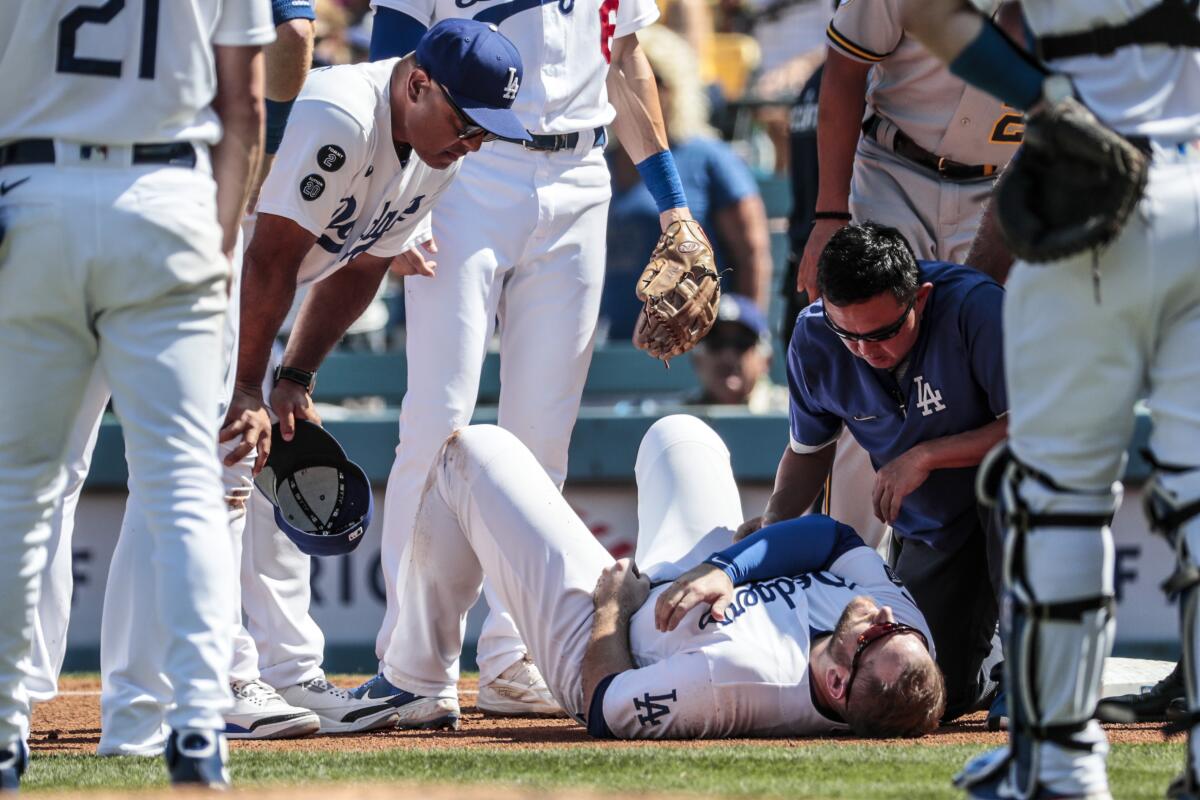 Team trainer Neil Rampe, right, and manager Dave Roberts talk to Max Muncy.