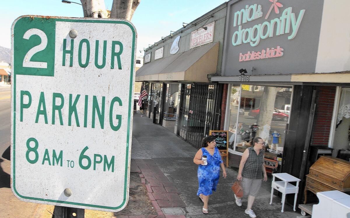 Pedestrians shop along Magnolia Blvd. with two-hour parking signs on display on Friday, October 3, 2014.