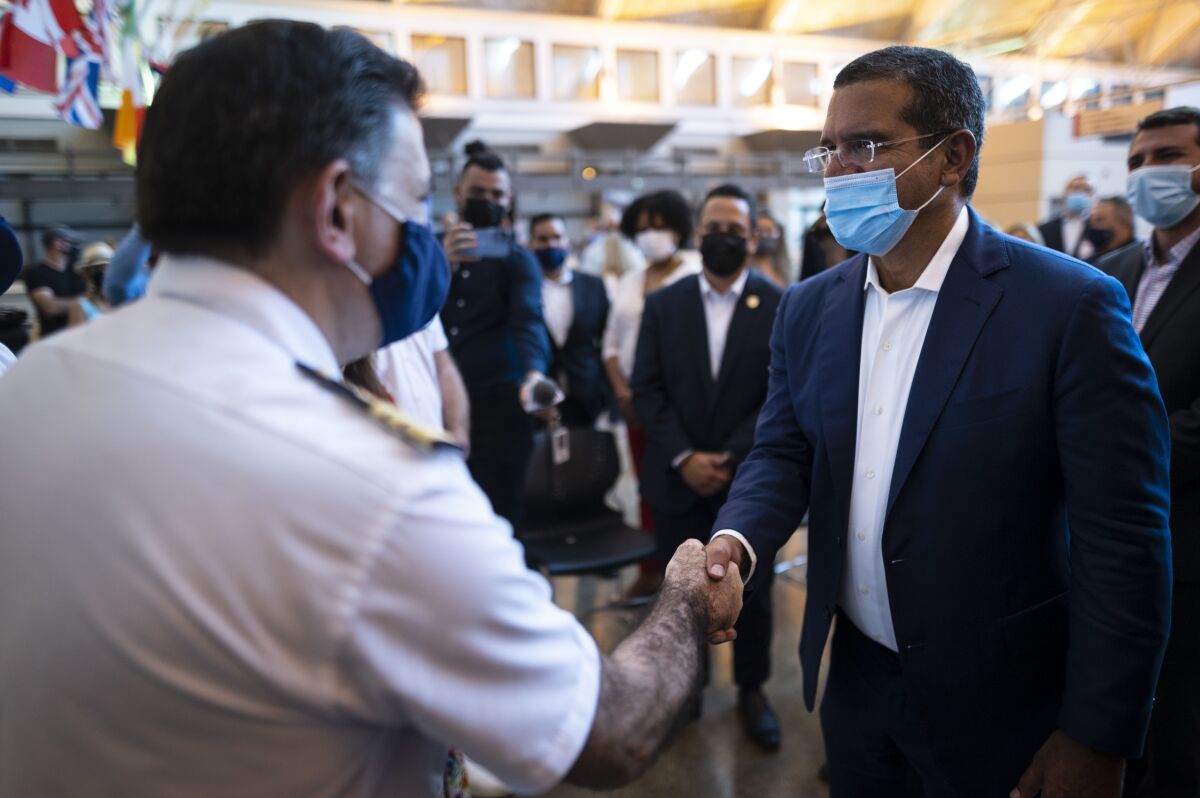Puerto Rican Governor Pedro Pierluisi greets crew members of Carnival's Mardi Gras cruise ship, docked in the bay of San Juan, Puerto Rico, Tuesday, Aug. 3, 2021, marking the first time a cruise ship visits the U.S. territory since the COVID-19 pandemic began. (AP Photo/Carlos Giusti)