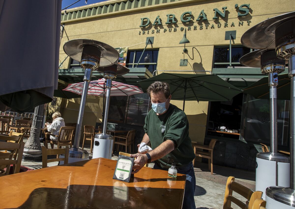 Dargan's owner Liam Sherlock cleans table outside his pub on Main St. in Ventura.