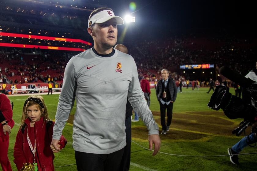 LOS ANGELES, CA - NOVEMBER 26, 2022: USC head coach Lincoln Riley holds his daughter's hand as he leaves the field after the Trojans beat Notre Dame at the Coliseum on November 26, 2022 in Los Angeles, California.(Gina Ferazzi / Los Angeles Times)