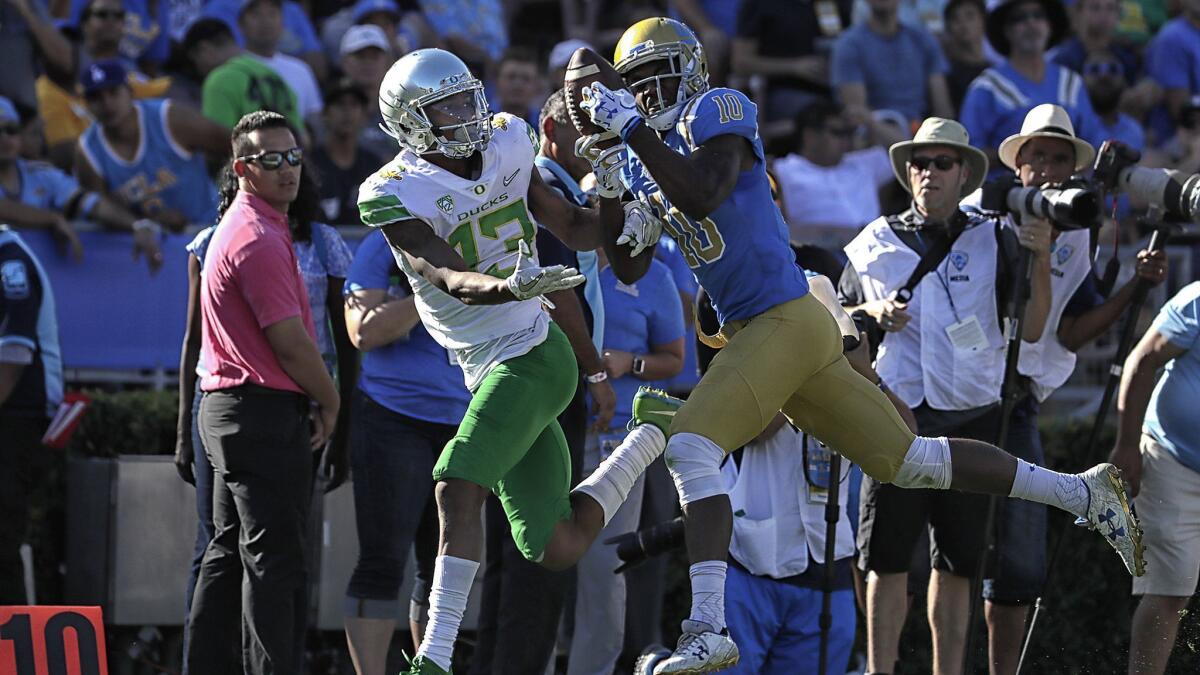 UCLA defensive back Colin Samuel, right, intercepts a pass intended for Oregon's Dillon Mitchell during a game at the Rose Bowl in October.