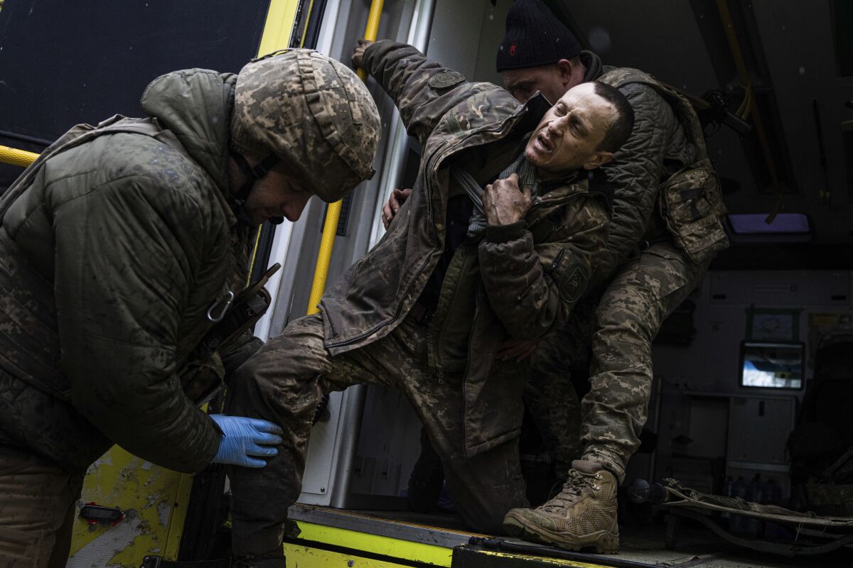 Médicos militares ucranianos ayudan a su camarada herido a salir de una ambulancia 