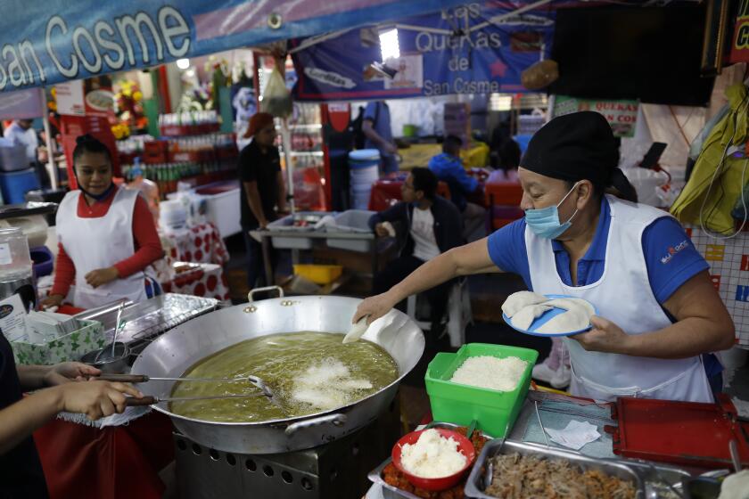 Sabina Hernandez Bautista, 59, prepares food in a stall inside Mercado San Cosme, where some vendors have put in place their own protective measures against coronavirus while others continue to work without masks or barriers, in Mexico City, Thursday, June 25, 2020. "We are all afraid," said Bautista, who added she had no choice but to work to be able to feed her family, including her daughter who is attending university. (AP Photo/Rebecca Blackwell)