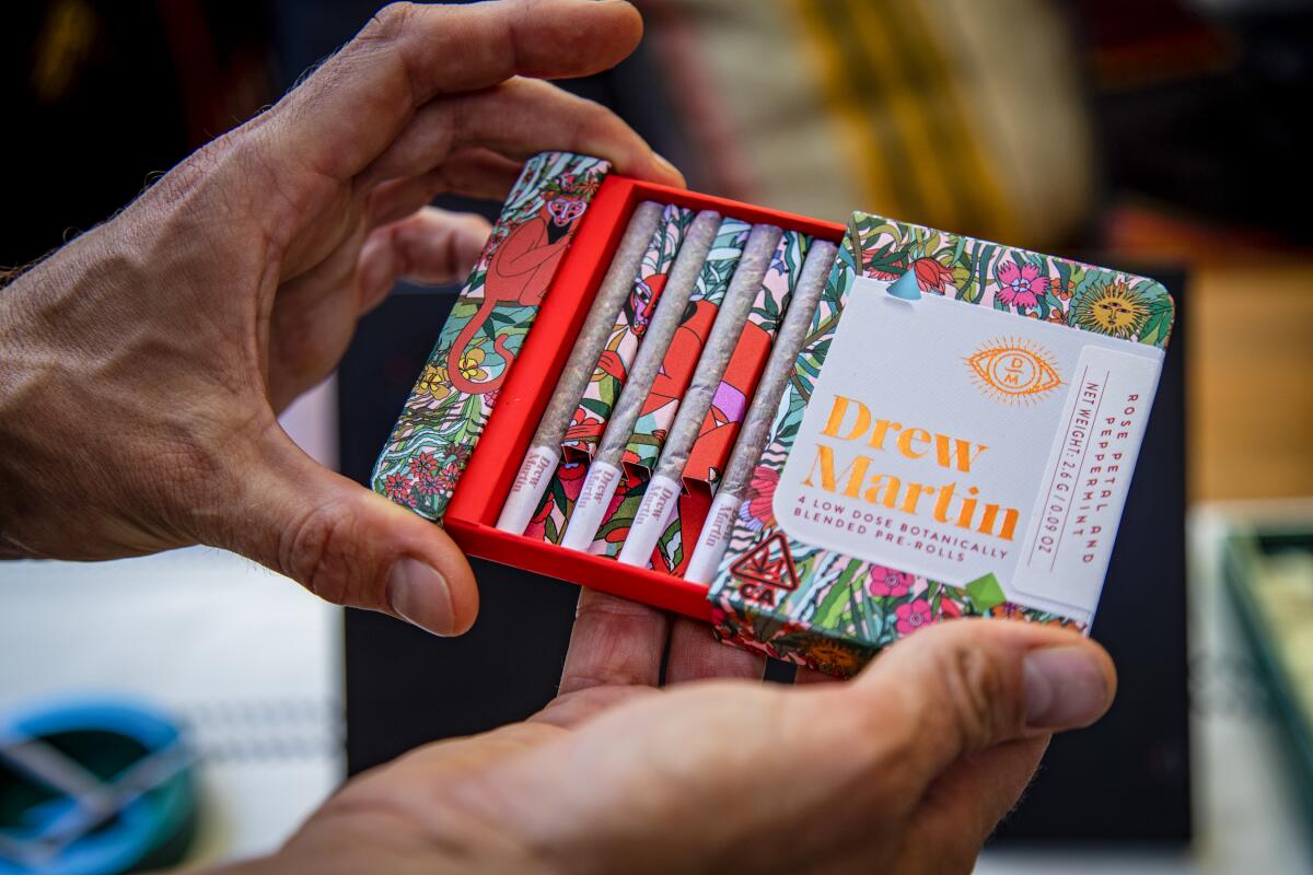A pair of hands holding a decorated box containing pre-rolled joints