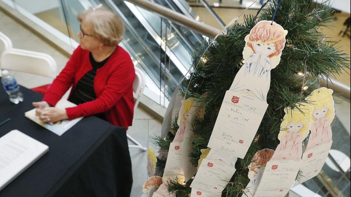 Volunteer Kathrine Richards looks for her replacement as she sits with an Angel Tree, on display with cards to take in front of Burlington Coat Factory in the Burbank Town Center.