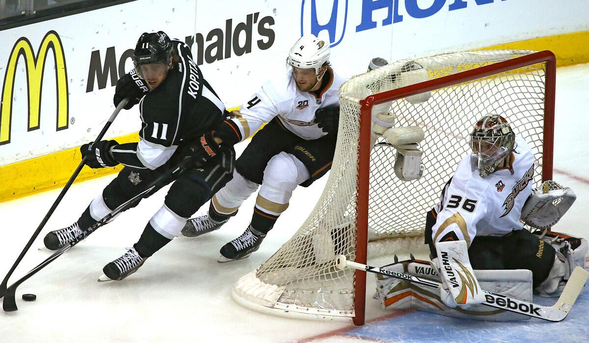 Ducks rookie goaltender John Gibson, making his first start in the playoffs, slides across the crease as Kings center Anze Kopitar tries to beat defenseman Cam Fowler around the net in the first period of Game 4 on Saturday night at Staples Center.