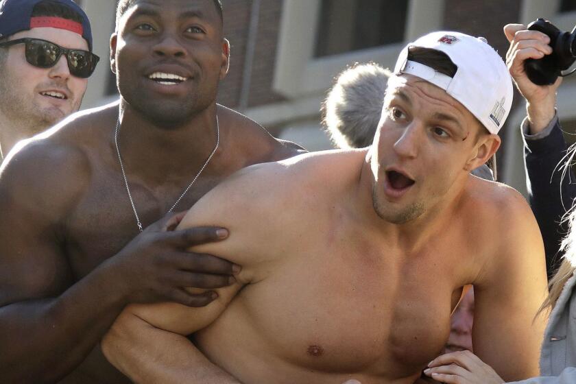 FILE - In this Tuesday, Feb. 5, 2019 file photo, New England Patriots tight ends Dwayne Allen, left, and Rob Gronkowski react to fans during the team's parade through downtown Boston to celebrate their win over the Los Angeles Rams in Sunday's NFL Super Bowl 53 football game in Atlanta. Gronkowski said he was hit in the face by a can of beer thrown during the parade, causing a small cut near his left eye. (AP Photo/Elise Amendola)