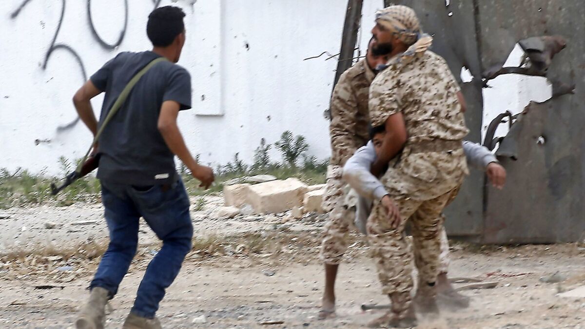 Fighters for Libya's internationally recognized government carry a wounded comrade during a firefight against forces loyal to Khalifa Haftar on Tuesday south of the capital, Tripoli.