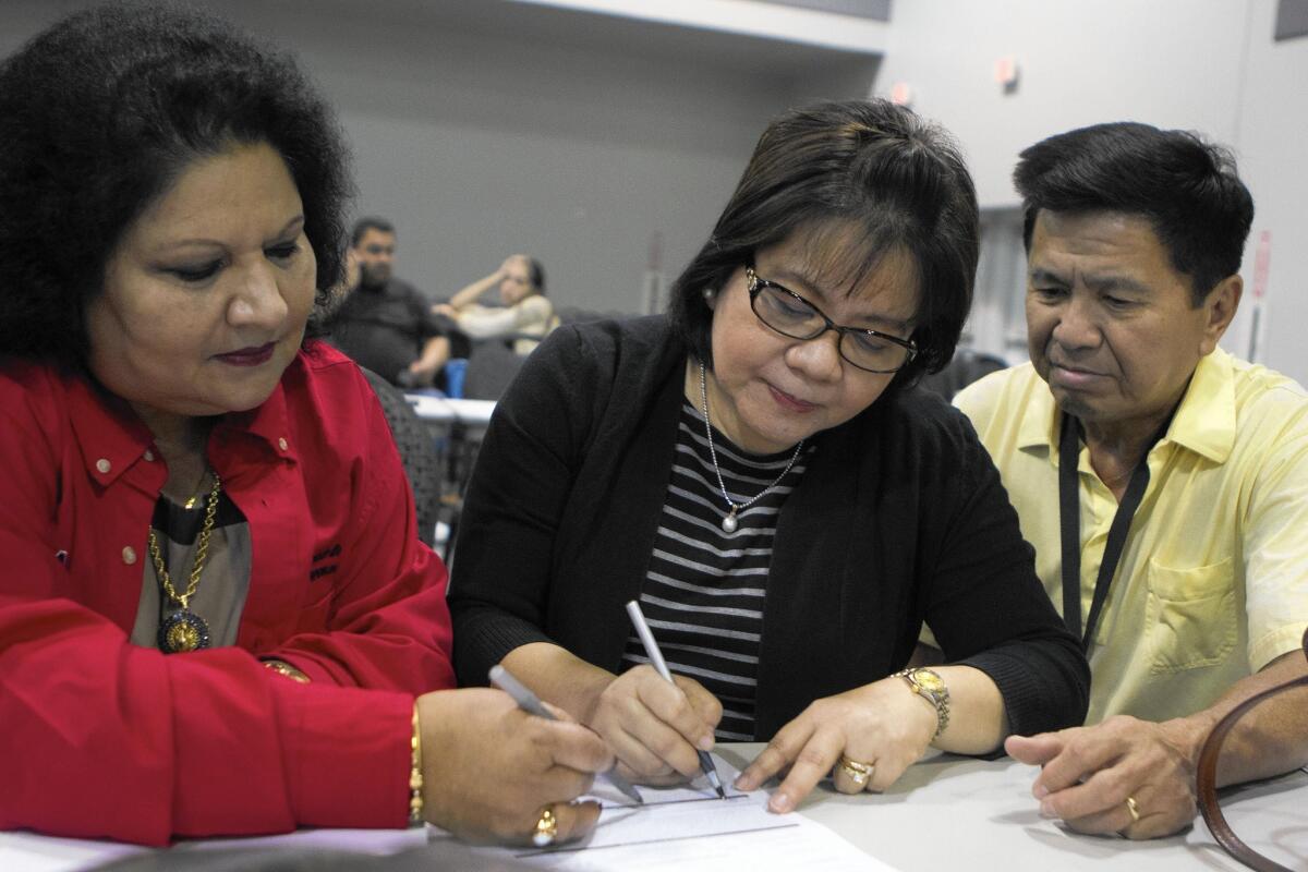 Mortgage consultant Anna Datta, left, helps Grace and Armando Ong sign up for a 15-year home loan at a Neighborhood Assistance Corp. of America event at the Ontario Convention Center.
