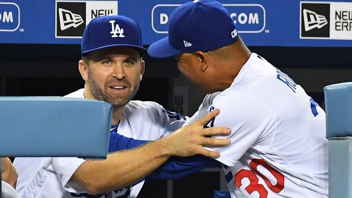 Newly acquired second baseman Brian Dozier says hello to Dodgers manager Dave Roberts as Dozier arrived in the dugout in the ninth inning against the Milwaukee Brewers at Dodger Stadium on Tuesday.