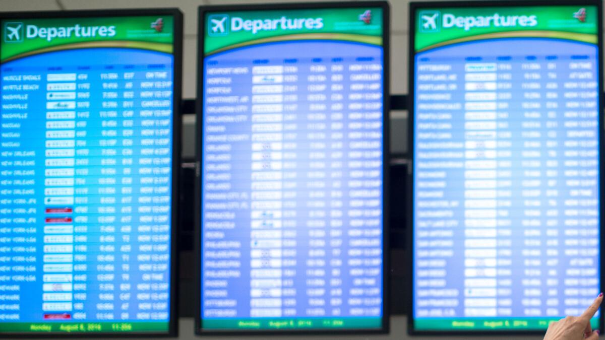 Travelers monitor boards at Hartsfield–Jackson Atlanta International Airport on Monday. Delta Air Lines delayed or canceled hundreds of flights Monday after its computer systems crashed, stranding thousands.