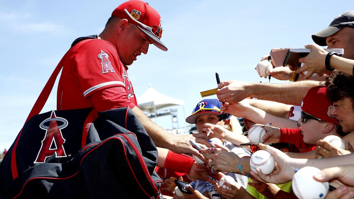 Angels center fielder Mike Trout signs autographs for fans before a spring training game against the Cincinnati Reds on March 8.