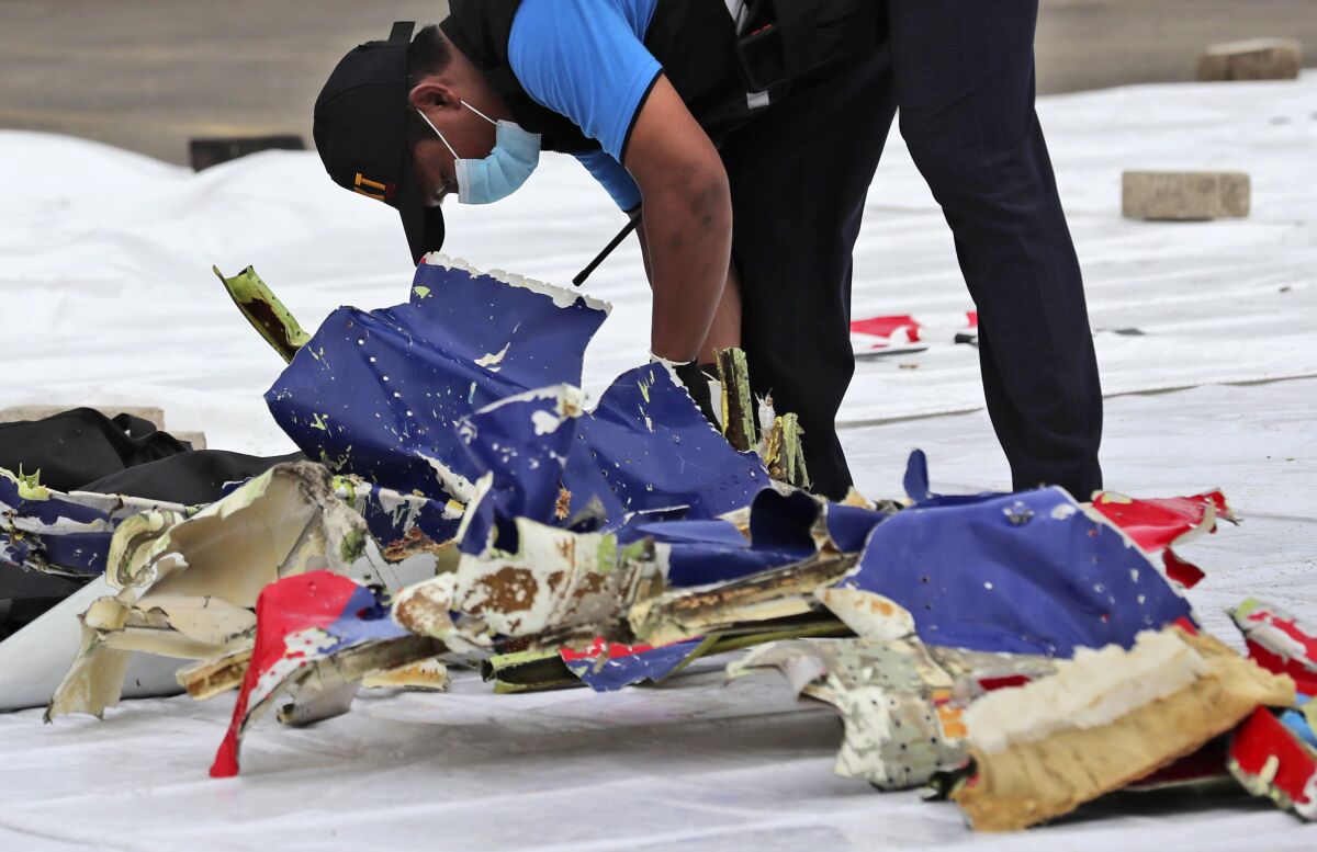 An investigator inspects parts of Sriwijaya Air Flight 182 that crashed. 