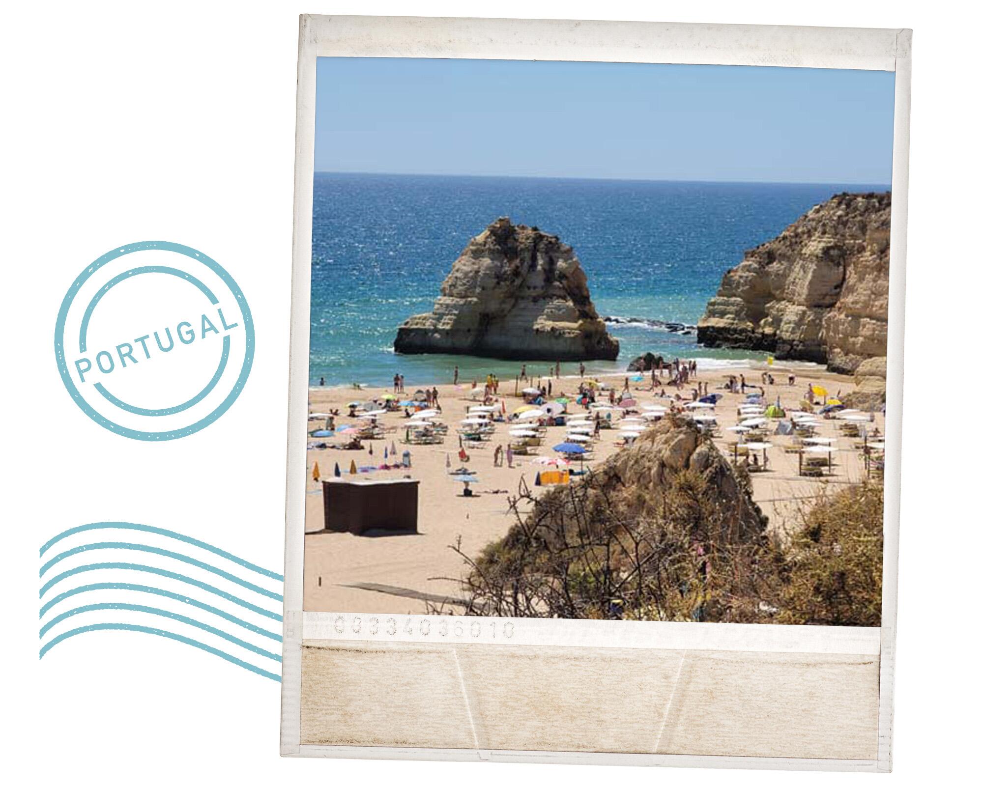 a view of a crowded beach near rocks in Portugal.