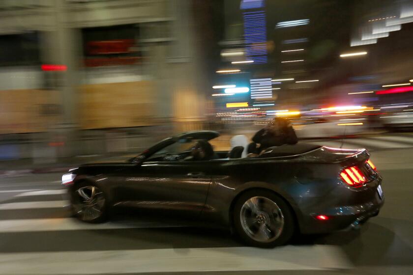 LOS ANGELES, CALIF. - MAY 30, 2020. Motorists go on a jjoyride down Main Street in downtown Los Angeles despite an 8 p.m. curfew on Saturday, May 30, 2020. About 200 people marched through downtown streets, slowing traffic and keeping ahead of police trying to cut them off. Looting and the destruction of public and private property has spread across the country in the wake of the the police killing of George Floyd, a black man in Minneapolis. (Luis Sinco/Los Angeles Times)