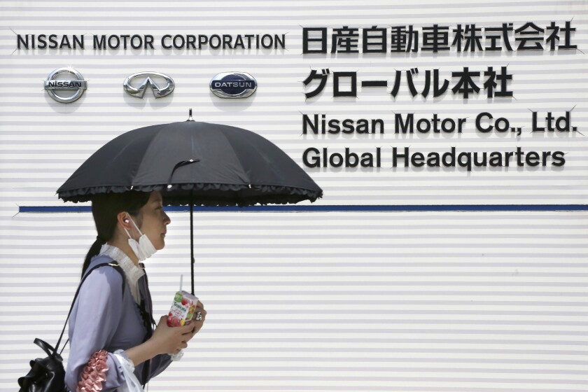 FILE - A woman walks past the global headquarters of Nissan Motor Co., Ltd. in Yokohama near Tokyo, Wednesday, May 27, 2020. The French-Japanese auto alliance of Renault and Nissan plans to invest 23 billion euros ($26 billion) in electric vehicle technology over the next five years, the companies said Thursday, Jan. 27, 2022. (AP Photo/Koji Sasahara, File)
