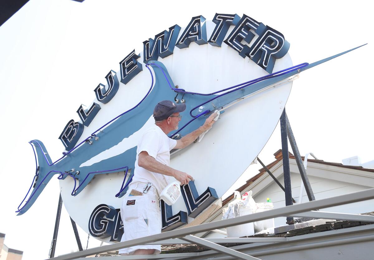 The Bluewater Grill neon sign gets a finish from Tony Calcagno as the restaurant is set to reopen in Newport Beach.
