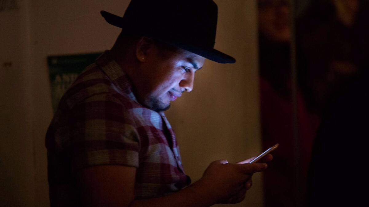 Yosimar Reyes, co-organizer of the show, checks his phone at the Boyle Heights Arts Conservatory.