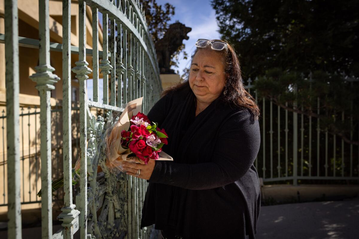 A woman places flowers in the gate of a home.