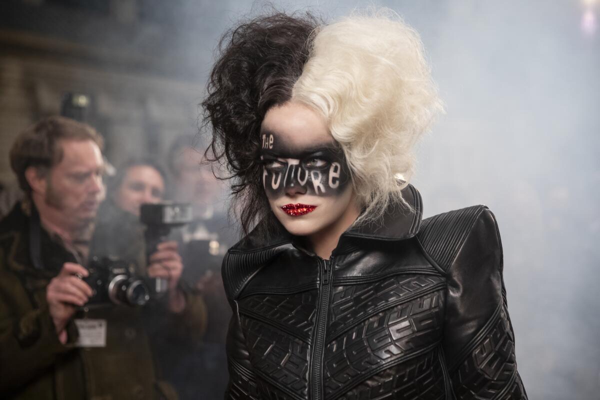 Emma Stone with half-white, half-black hair, a black jacket and the words "The Future" painted like a mask on her face