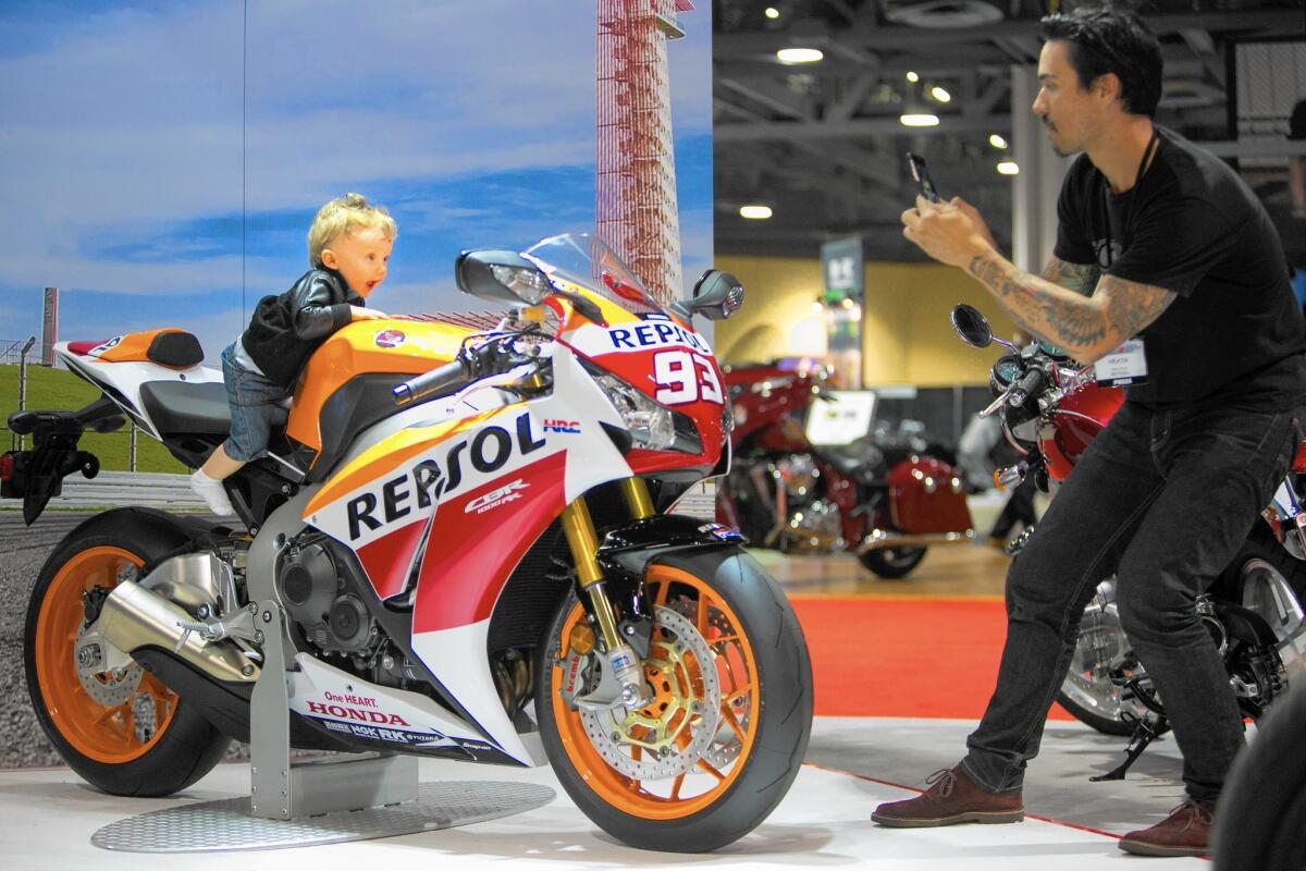 Charlie Cofran, 10 months old, sits on a Honda CBR1000 RR motorcycle with Moto GP decals and is photographed by his father, Heath, at the Progressive International Motorcycle Show at the Long Beach Convention Center in Long Beach.