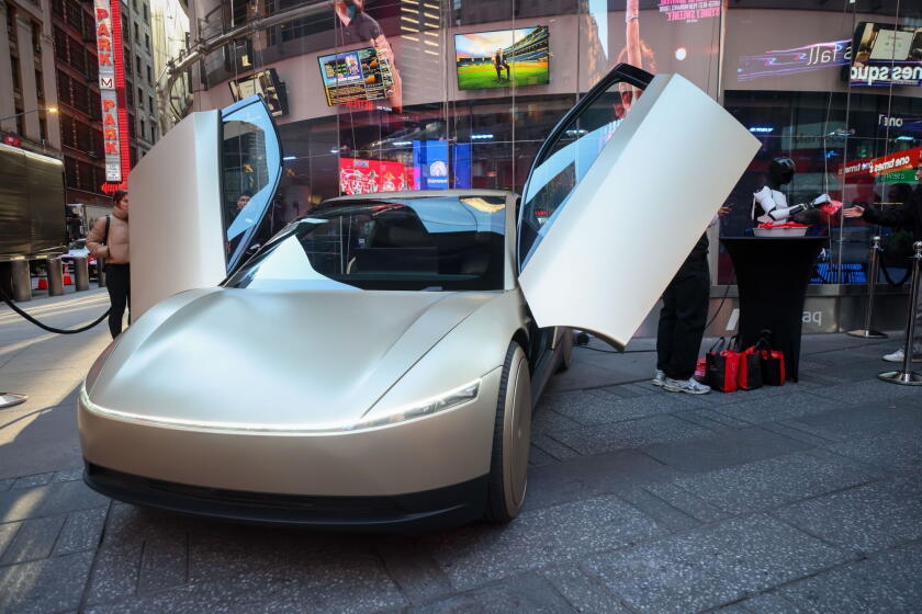 A Tesla Optimus robot, right, and a Tesla Cybercab prototype.
