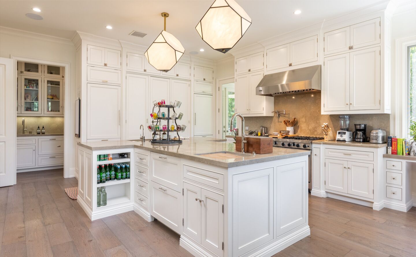 The kitchen is white with overhead lighting fixtures and an island.