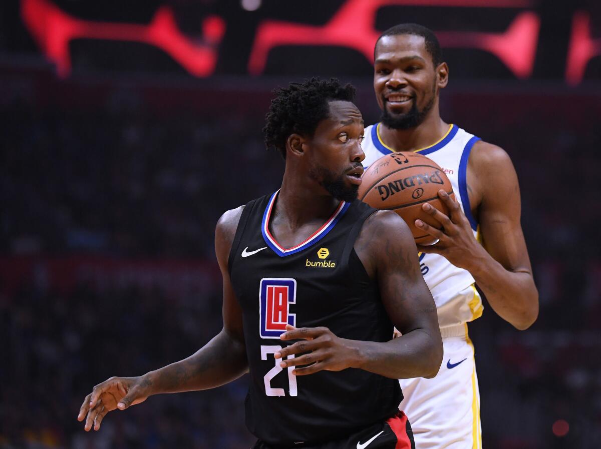 Patrick Beverley #21 of the LA Clippers looks back at a smiling Kevin Durant #35 of the Golden State Warriors during Game Two of Round One of the 2019 NBA Playoffs at Staples Center on April 18, 2019 in Los Angeles, California.