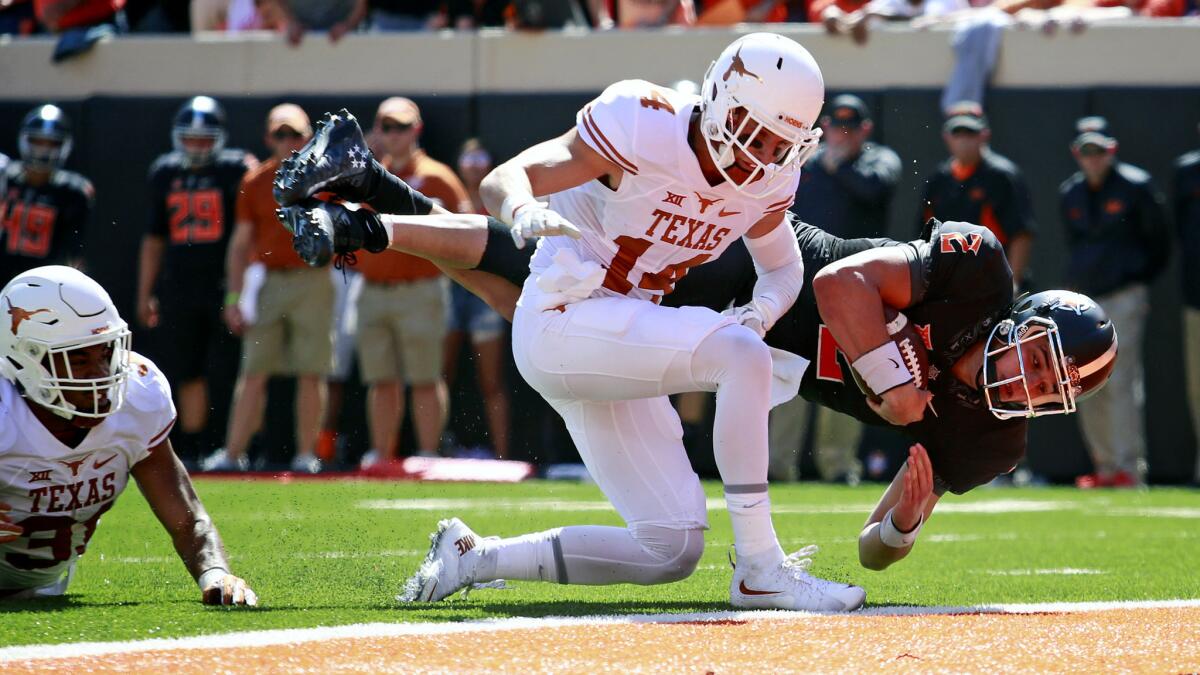 Oklahoma State quarterback Mason Rudolph dives across the goal line as he's hit by Texas Dylan Haines during their game Saturday.