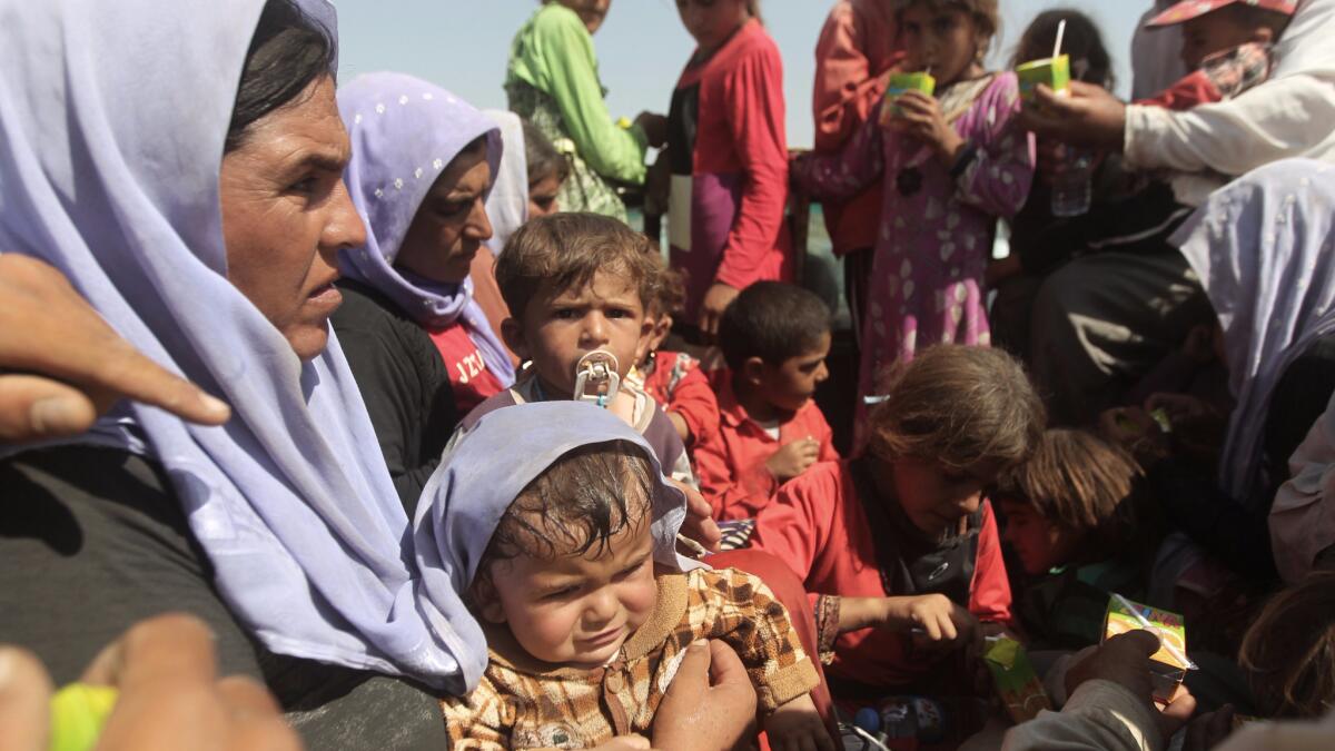 In this 2014 file photo, displaced Iraqi families from the Yazidi community rest after crossing the border with Syria in northern Iraq.