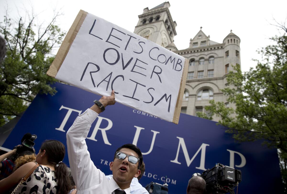 Armando Garcia holds up a sign in protest of Republican presidential candidate Donald Trump and his portrayal of Mexican immigrants as criminals outside the new Trump hotel in Washington on Thursday. Trump is scheduled to speak in Los Angeles on Friday, and a protest rally is planned.