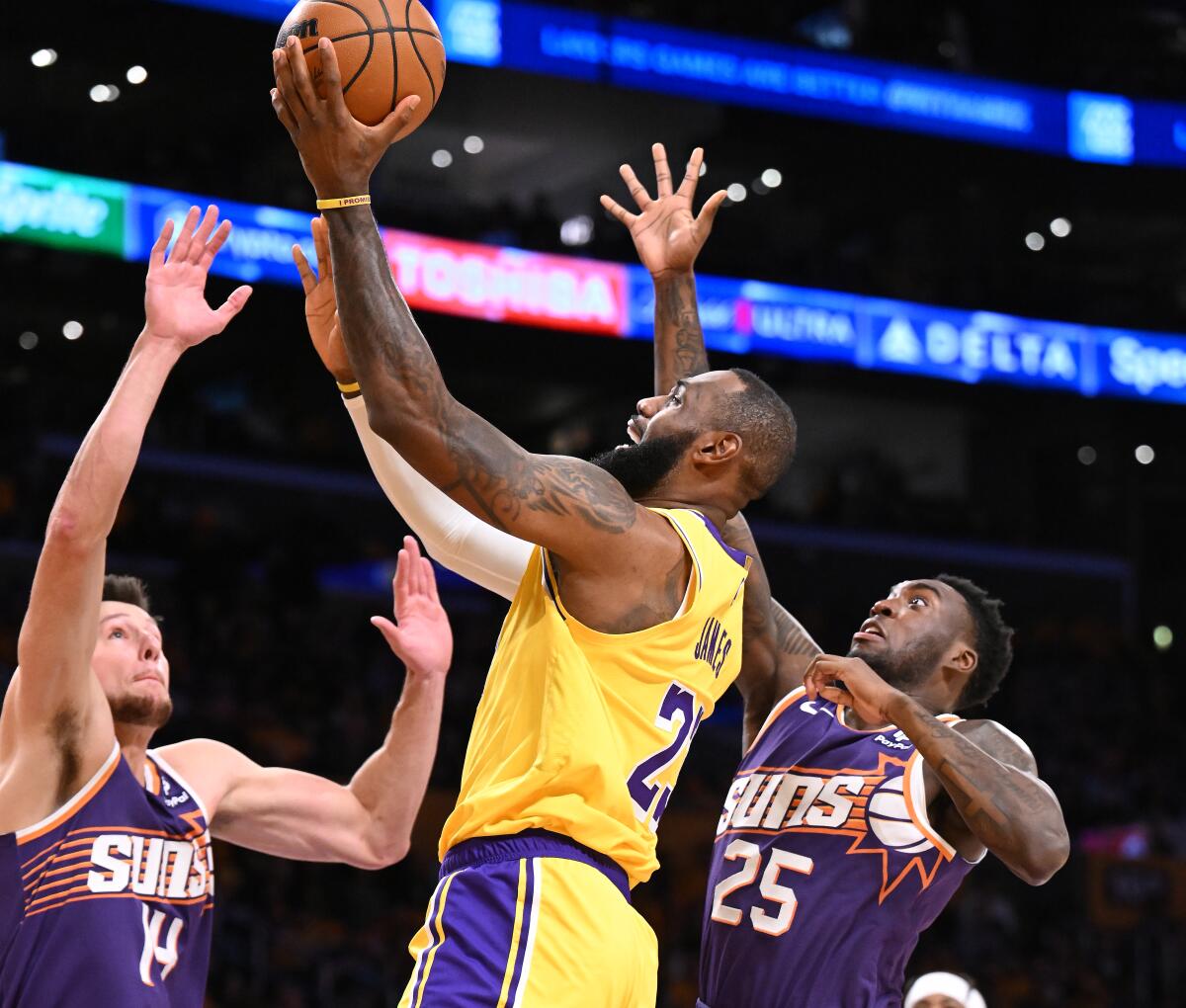 Lakers star LeBron James drives to the basket between Phoenix Suns center Drew Eubanks and forward Nassir Little.