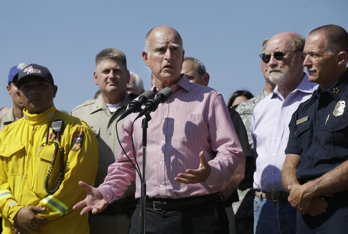 Gov. Jerry Brown, center, surrounded by firefighters and first responders, speaks at a news conference at Cowboy Camp Trailhead during the Rocky fire in August.