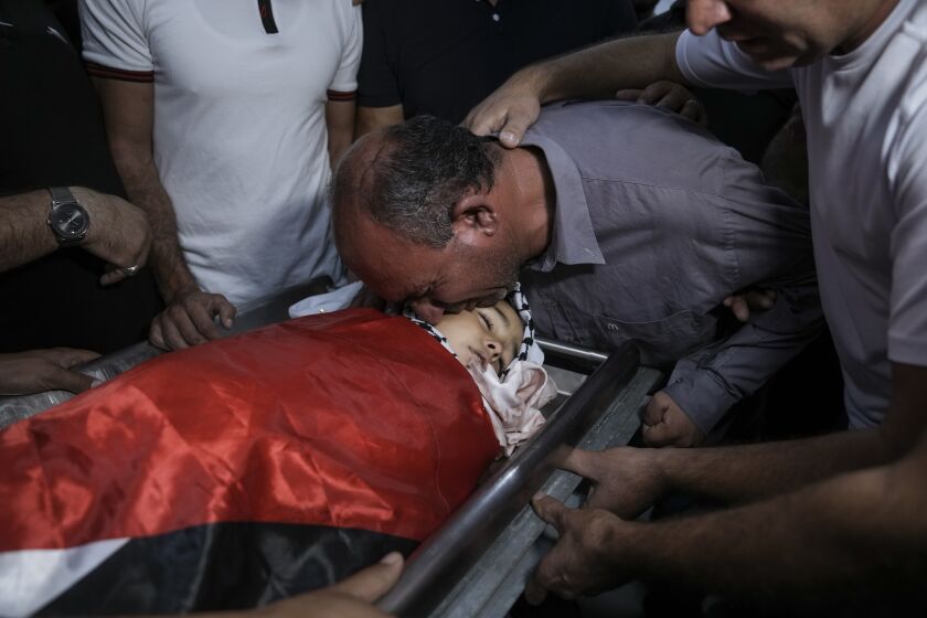 Father of 7-year-old Palestinian boy Rayan Suleiman, kisses his body at a hospital in the West Bank village of Beit Jala just before his funeral Friday, Sept. 30, 2022. The U.S. State Department has called on Israel to open a "thorough" investigation into the mysterious death of the boy, who collapsed and died shortly after Israeli soldiers came to his home in the occupied West Bank. Relatives said he had no previous health problems and accused the army of scaring the child to death. The army called the death a tragedy and said its soldiers were not to blame. (AP Photo/Mahmoud Illean)