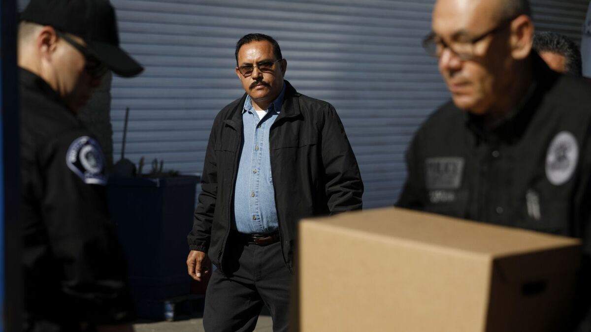City of Maywood Mayor Ramon Medina keeps an eye on investigators with the Los Angeles County District Attorney's Office in February while they remove items as part of an investigation into accusations of corruption in the city.