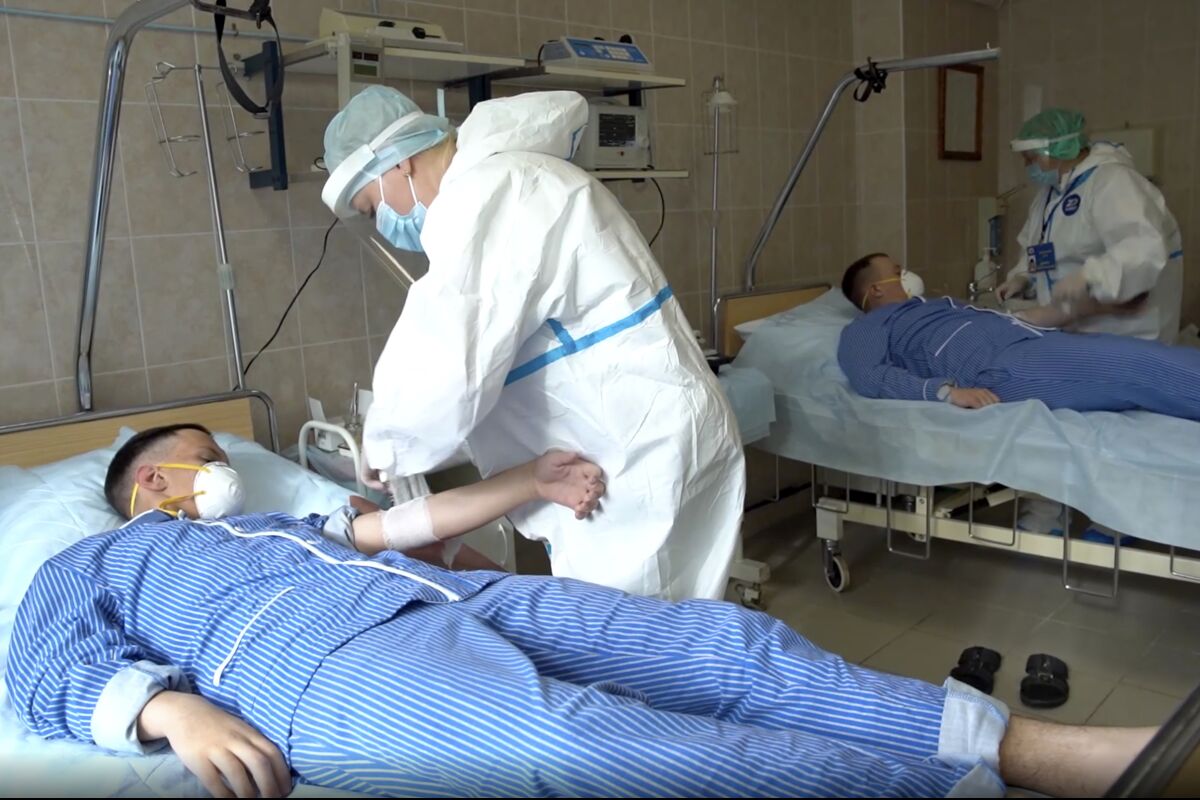 In this photo made from footage provided by the Russian Defense Ministry on Wednesday, July 15, 2020, medical workers in protective gear prepare to draw blood from volunteers participating in a trial of a coronavirus vaccine at the Budenko Main Military Hospital outside Moscow, Russia. Russia is boasting that it’s about to be the first country to approve a COVID-19 vaccine, but scientists worldwide are sounding the alarm that the headlong rush could backfire. (Russian Defense Ministry Press Service via AP)