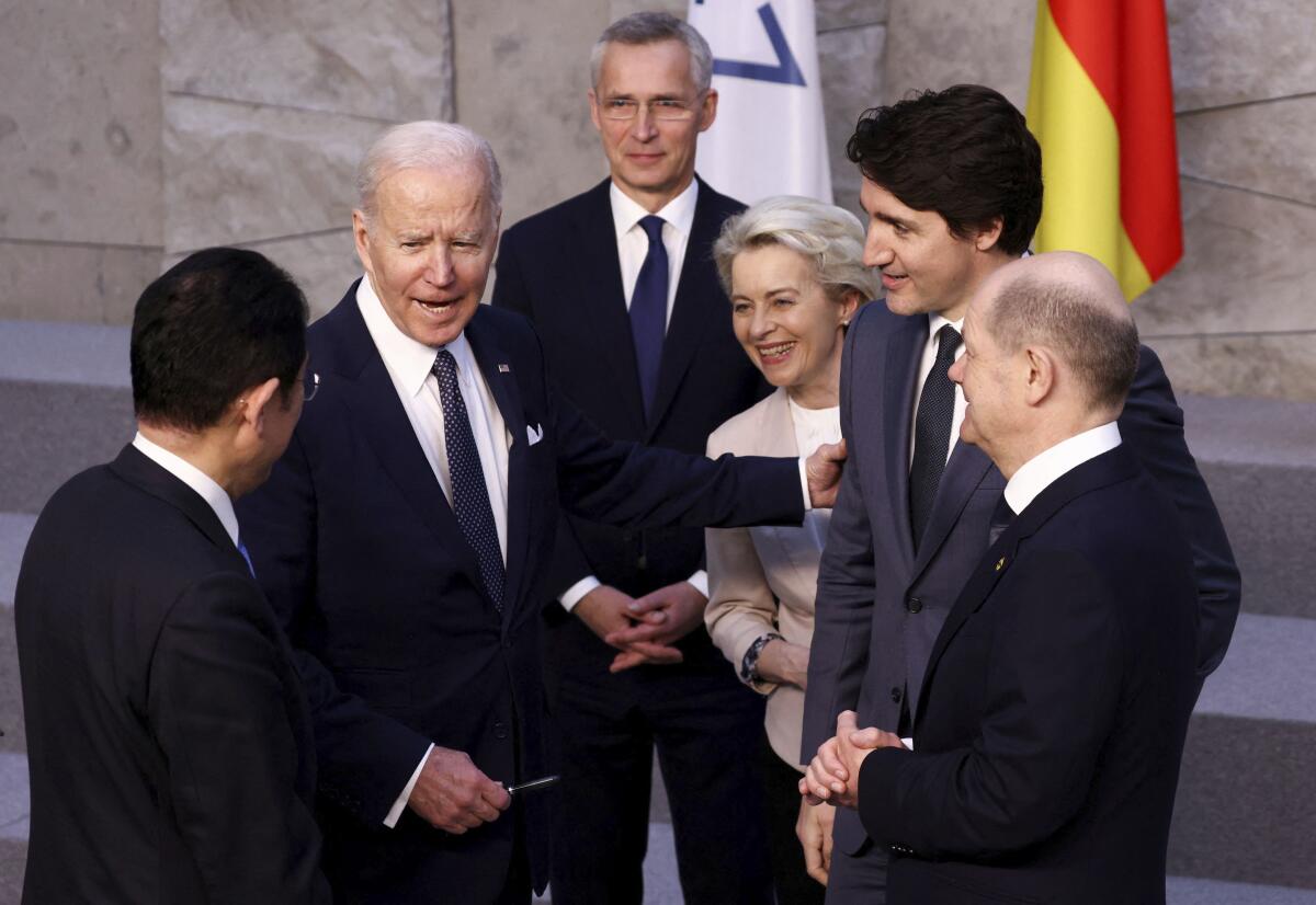 A group of six people in suits smile and talk