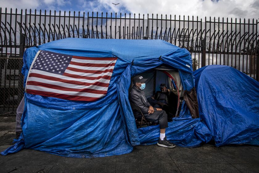 David Barker, 56, is visiting with his friend living in a tent on skid row in Los Angeles, Calif. on Thursday, March 19, 2020. David is not homeless but he works in the area. Because of the coronavirus pandemic city and county workers are working to move people living on the street inside.