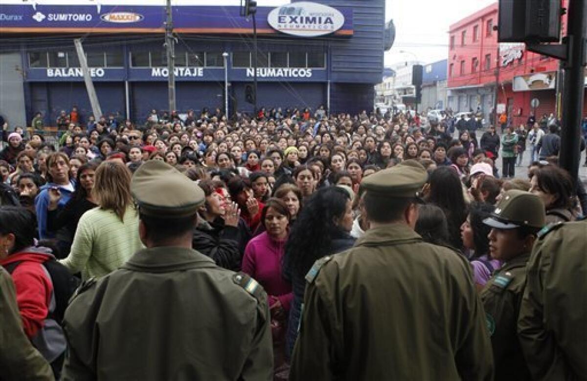 Police officers stand guard as people look on in front of a supermarket in Concepcion, Chile, Sunday, Feb. 28, 2010. A 8.8-magnitude earthquake hit Chile early Saturday. (AP Photo/ Natacha Pisarenko)