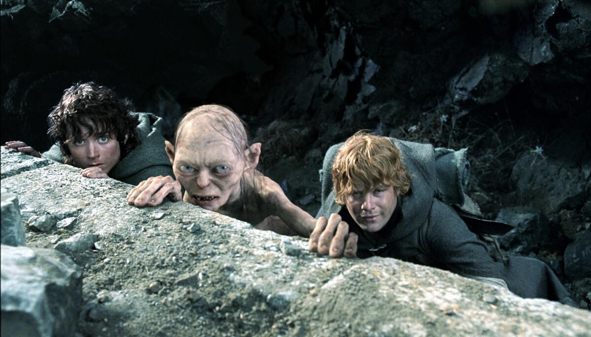 Andy Serkis' Gollum lurks behind a large rock flanked by hiding Hobbits played by Elijah Woods and Sean Astin
