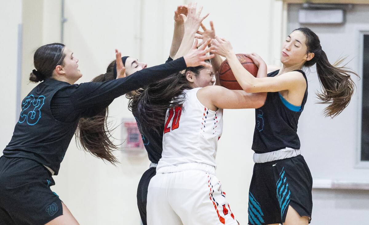 Huntington Beach's Marisa Tanga (20) battles with Aliso Niguel's Catherine Swanson, left, Karina Cabrera, center, and Sara Eyre, right, during the first round of the CIF Southern Section Division 1 playoffs on Thursday.
