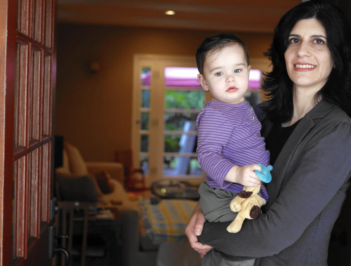 Debbie Kleinman holds her daughter Genevieve at home in Woodland Hills. Kleinman, a marketing research professional, is one of the nearly 54% of Californians who have work-based health insurance.
