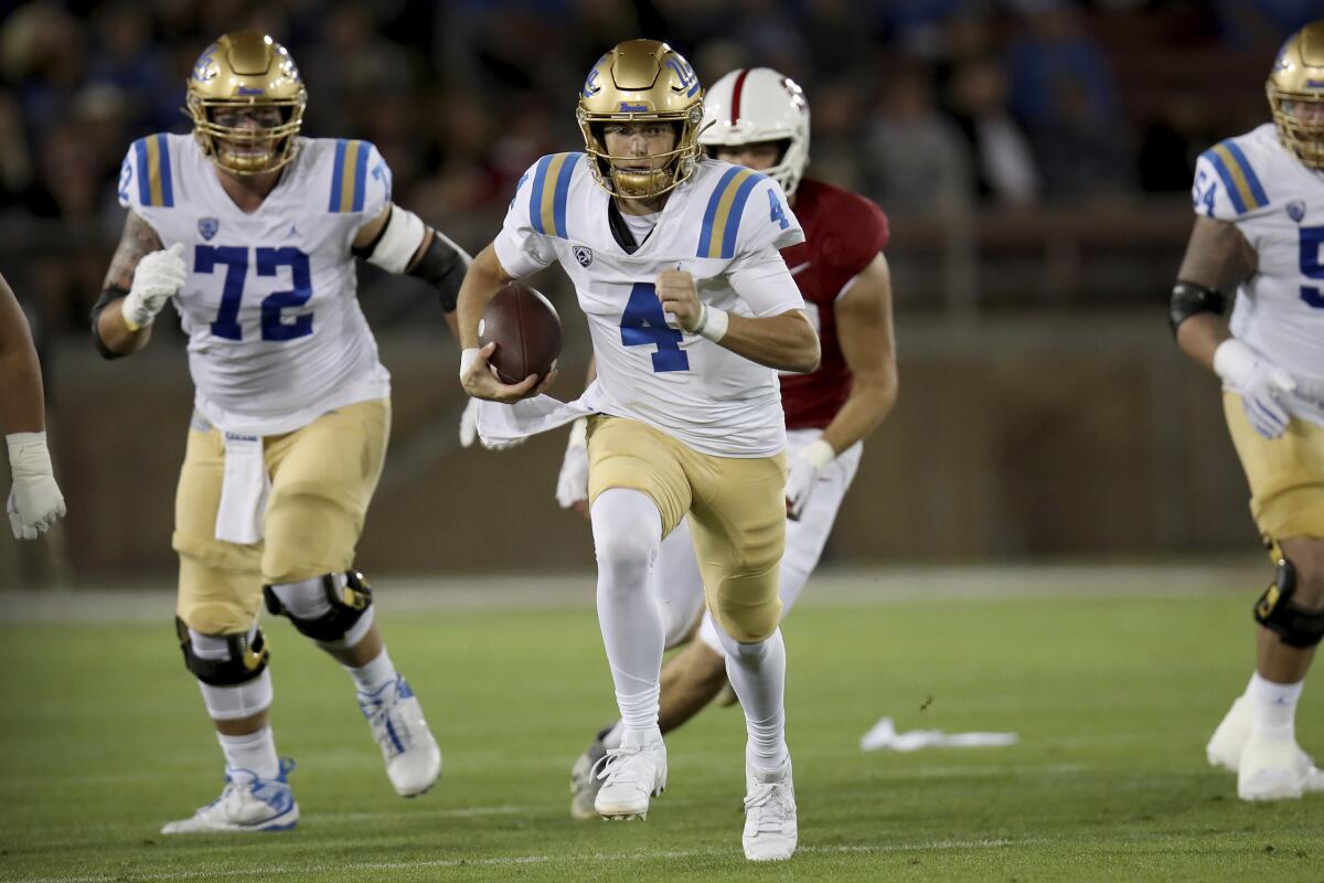 UCLA quarterback Ethan Garbers runs ahead of other players during an NCAA college football game.