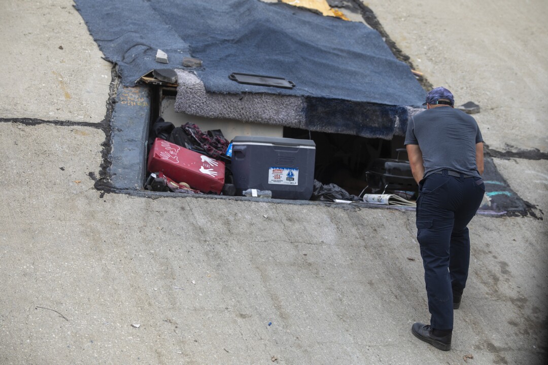 Daniel Newell with L.A. County Department of Health Services talks with a person living in a cavity on the creek bank.