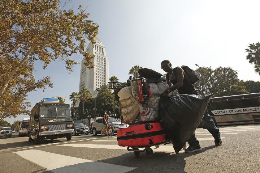 LOS ANGELES, CA - OCTOBER 09, 2019 A homeless individual moves his belongings back to the sidewalk on 1st Street between Spring and Broadway in downtown LA Wednesday morning after the department of streets and sanitation cleanup the area earlier this morning as the LAPD is increasing patrols around the Civic Center area because government employees have raised concerns about the homeless population in the area. (Al Seib / Los Angeles Times)