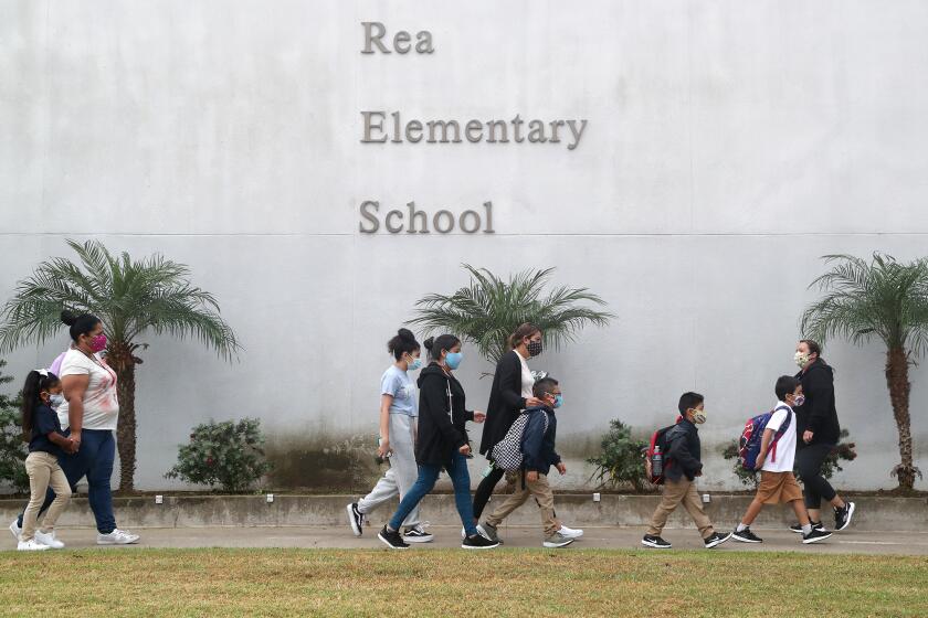 Students and parents walk to Rea Elementary School in Costa Mesa on Tuesday morning as the campus has reopened for fall classes.