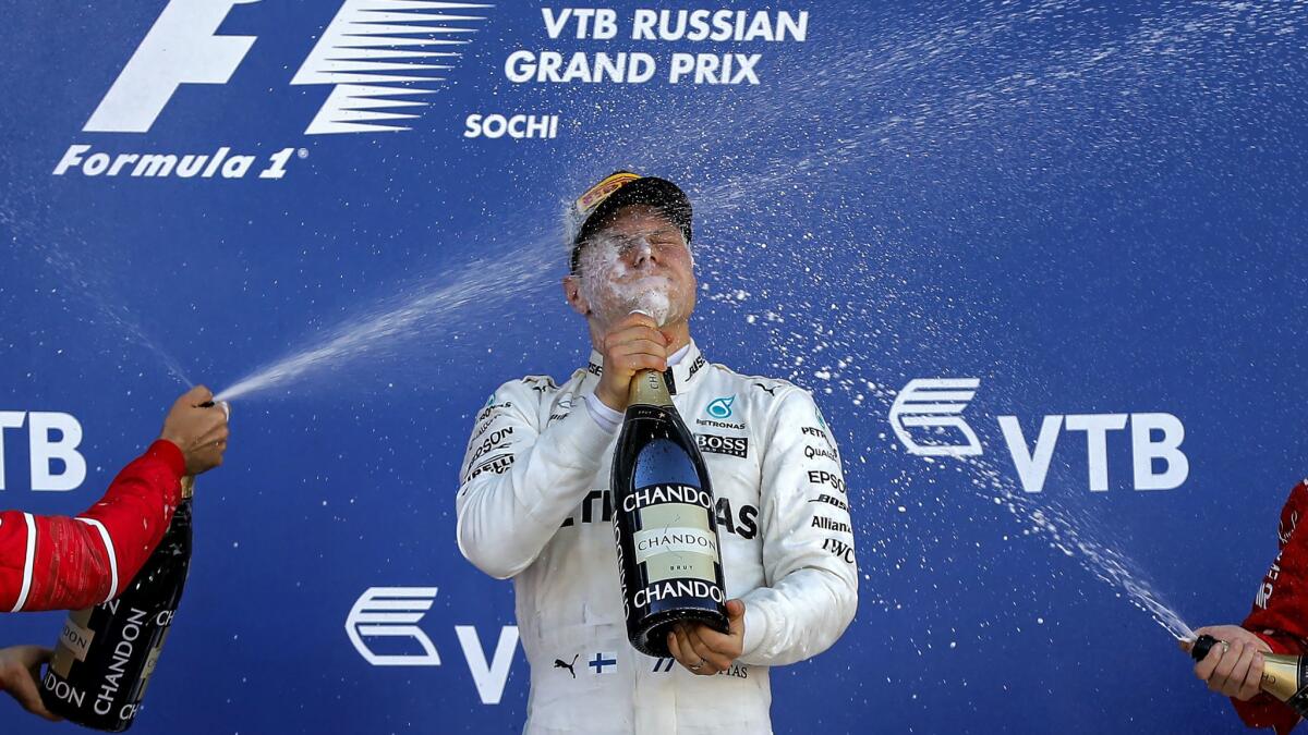 Formula One driver Valtteri Bottas is spayed with champagne by his rival on the podium after winning the Russian Grand Prix on Sunday