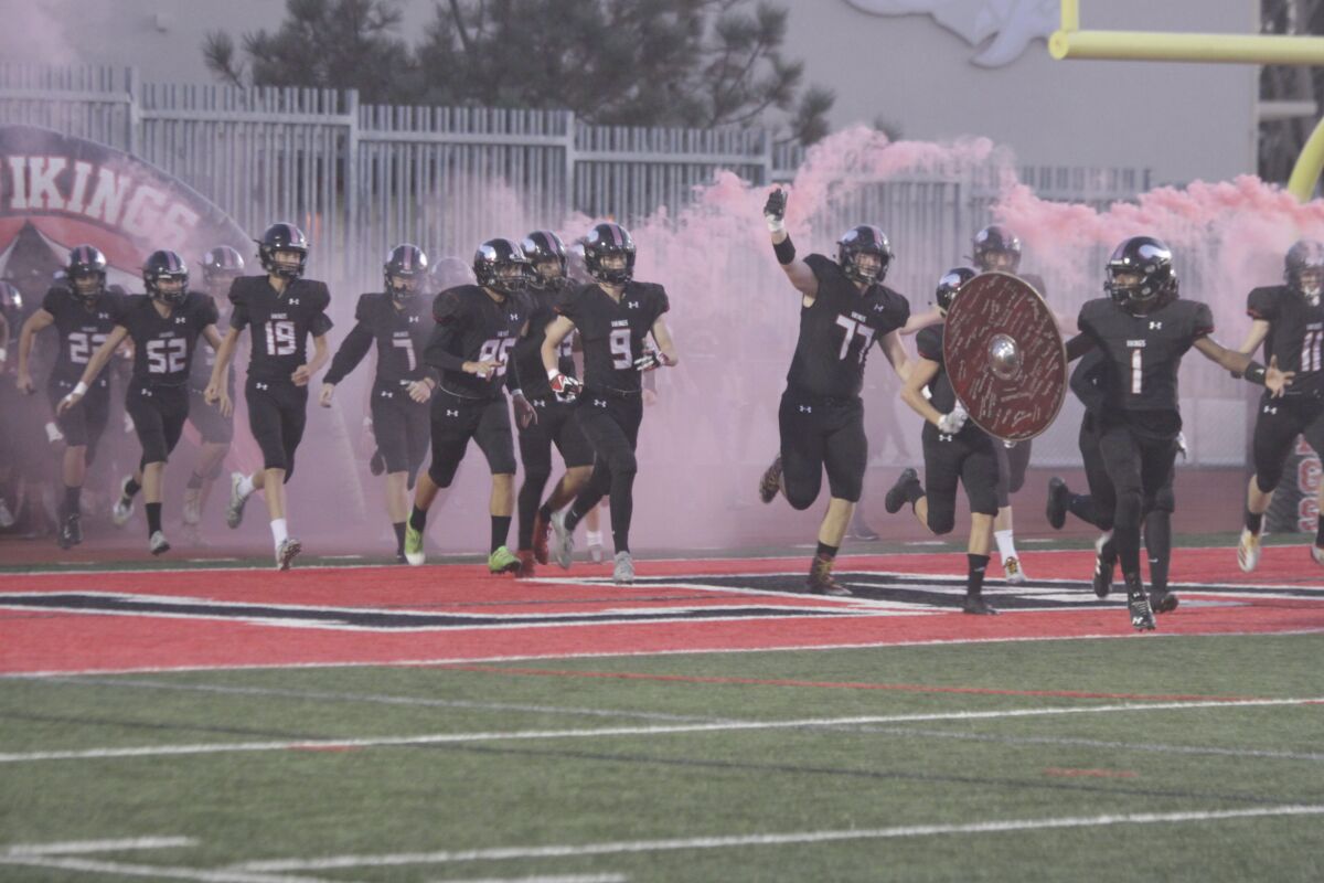 An excited La Jolla High School Vikings football team takes the field at Homecoming, Oct. 11, 2019 in what would be an action-packed game with its 35-12 victory against Morse High School.