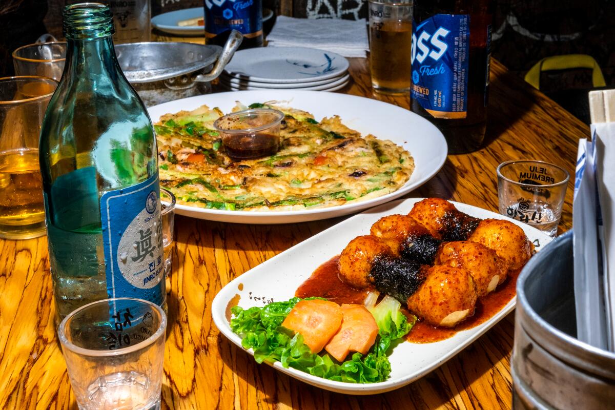 Dumbbells, or seaweed-wrapped fried dough, and a seafood pancake on a wooden table at Dan Sung Sa in L.A.'s Koreatown